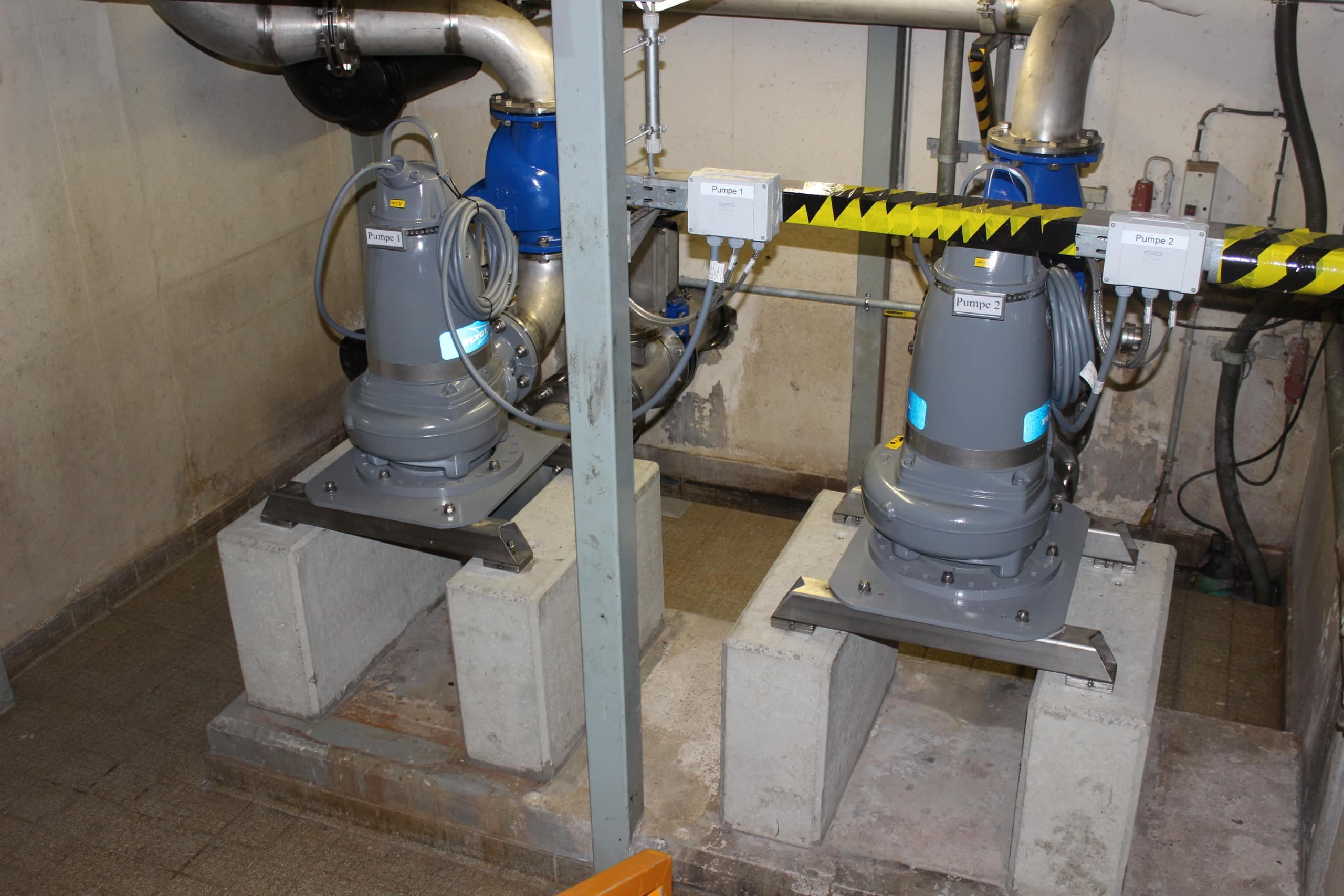 Zwei Abwasserpumpen auf Betonsockeln in einem Pumpwerk
